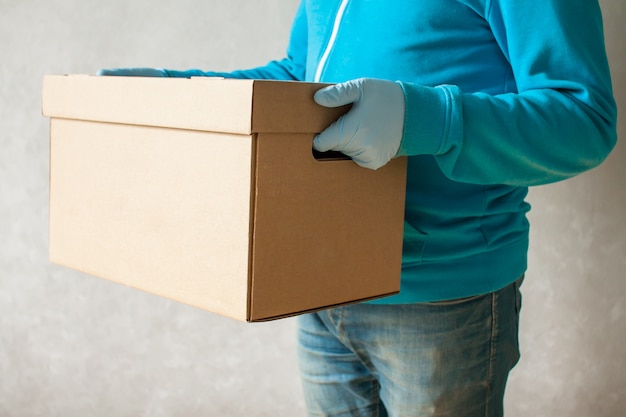 Man in rubber gloves and a medical mask delivers carton box