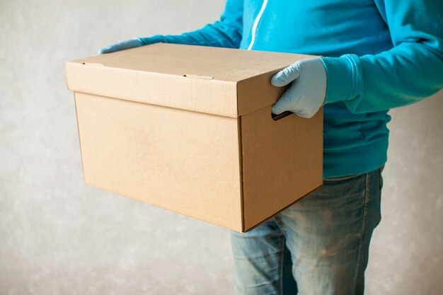 Man in rubber gloves and a medical mask delivers carton box