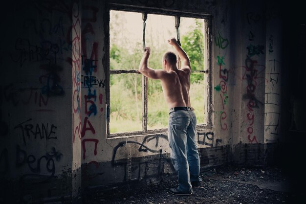 Foto l'uomo in rovina della casa guarda fuori dalla finestra 3479