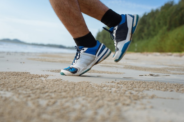 L'uomo corre sulla spiaggia, primo piano su scarpe