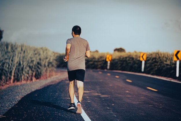 健康への道の男ランナーアスリート、路上で運動を実行している若者