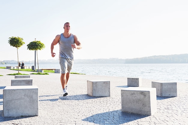 Man runner doing stretching exercise, preparing for morning workout in park.