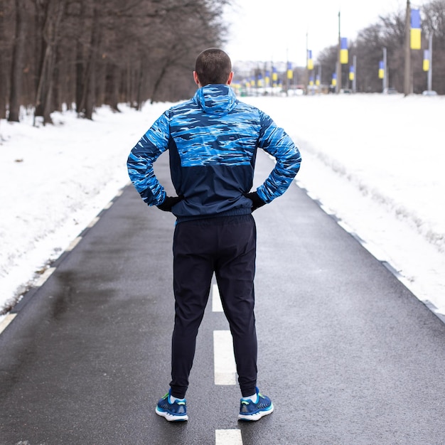 ランニングトラックに後ろから立って、走る前に道路を見ている男のランナー