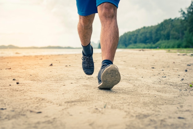 Photo man runner legs running closeup on shoe, men jogging on the beach