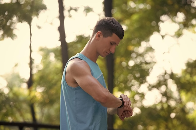 Man runner in sportswear checking time on smartwatch