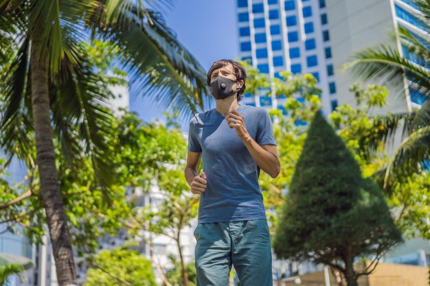 コロナウイルスの背景で都市で走っている医療マスクを着た男性ランナー