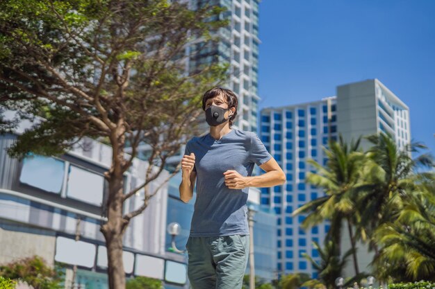 コロナウイルスの背景で都市で走っている医療マスクを着た男性ランナー