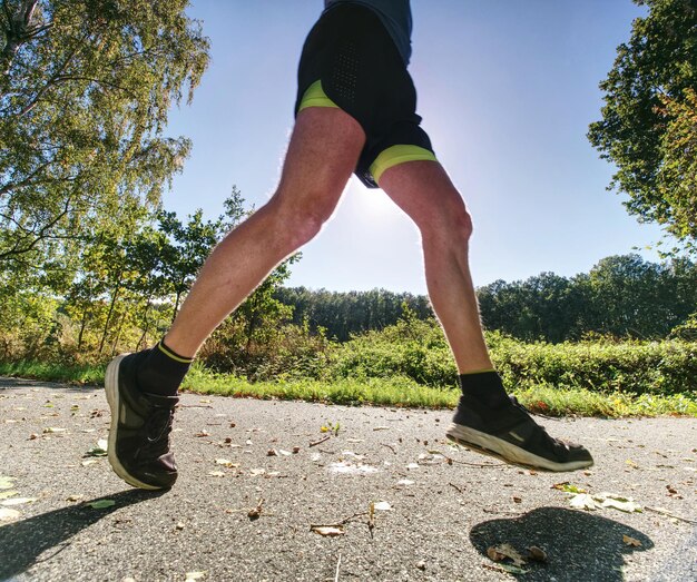 Photo man running on asphalt track athlete running fast in a park with dense trees in the background