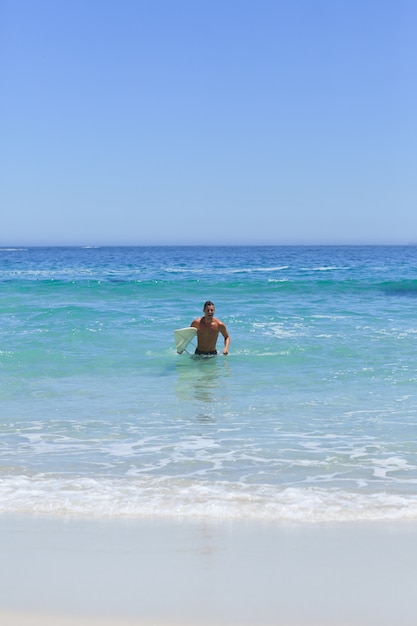 Man running on the beach with his surfboard