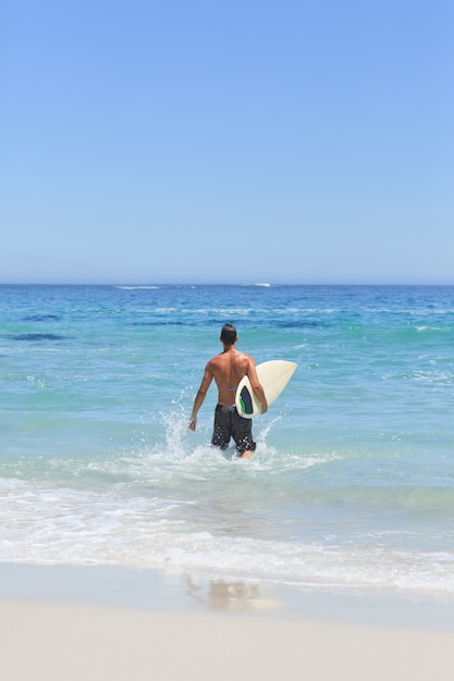 그의 서핑 보드와 함께 해변에서 실행하는 남자