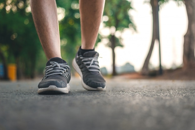 Foto uomo che corre sul parco con close up scarpe