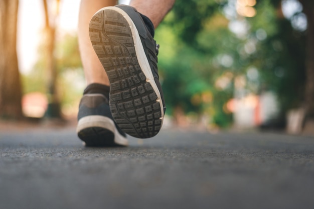 Uomo che corre sul parco con close up scarpe