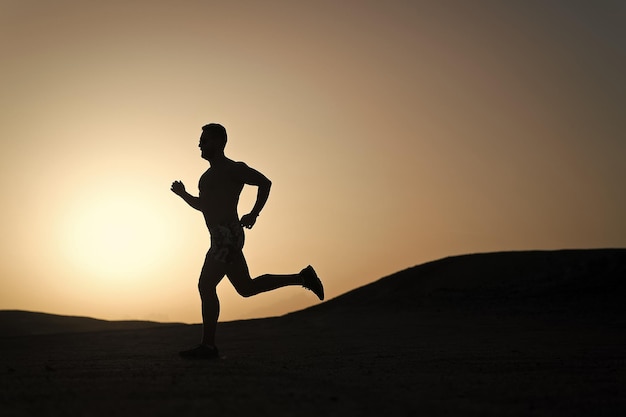 Man running silhouette on sunset background young caucasian run in mountain