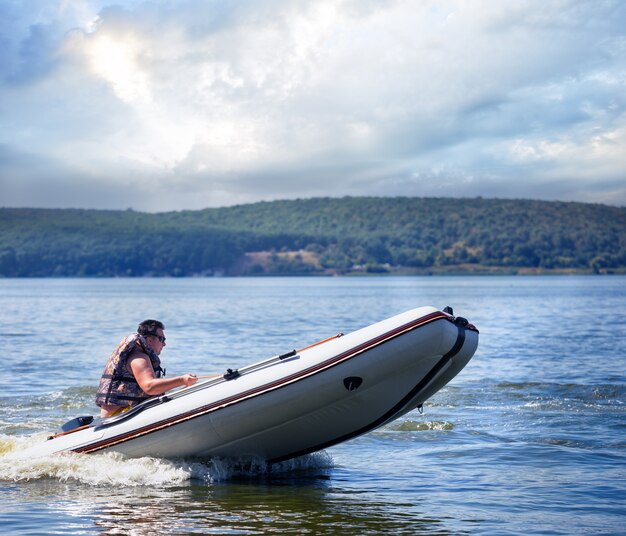 Man running white motor boat with orange stripes on the sides