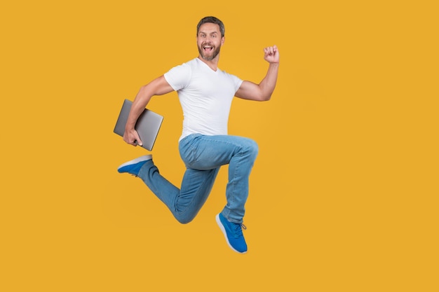 Man running with laptop has deadline Happy man midair yellow background