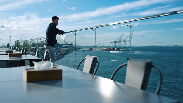 Man rust dakterras genieten van uitzicht op zee Peinzende zakenman op zoek poort