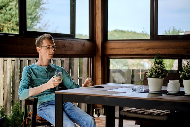 Man rust op de veranda met een glas wijn en reset een inkomende oproep