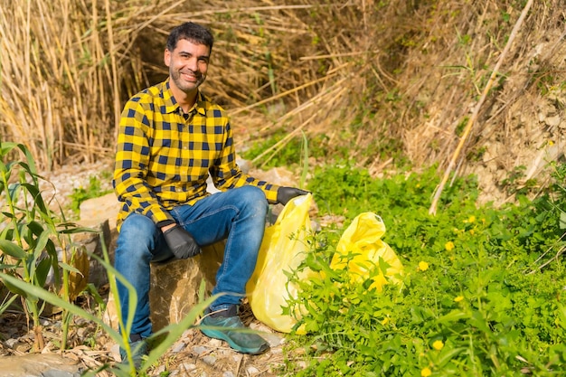 Man rustend van het oppakken van afval in een bos ecologie schone natuur van kunststoffen