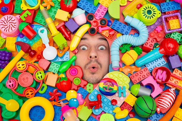 A man's face surrounded by building blocks and toys