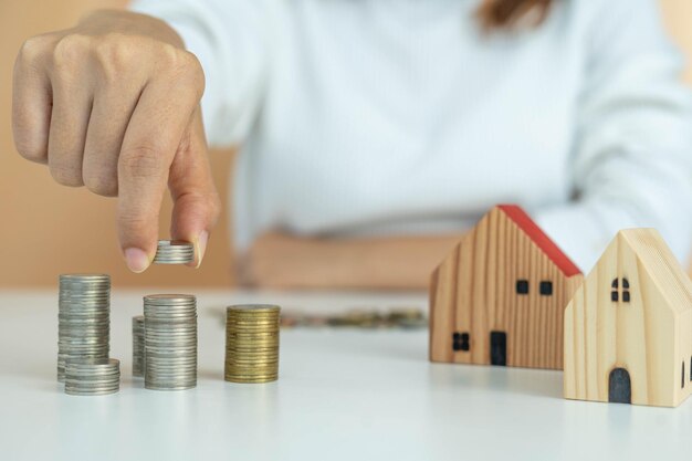 Il dito di un uomo tiene una pila di monete e analizza le entrate e le spese di crescita della moneta investire risparmi e debiti per costruire una casa