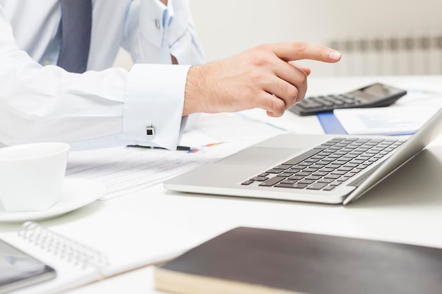 Man's finger pointing at his laptop screen