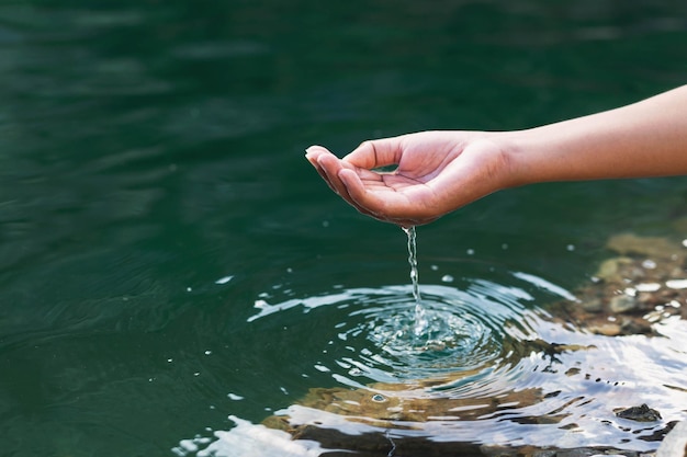 Man's hand aanraken van water midden in de natuur