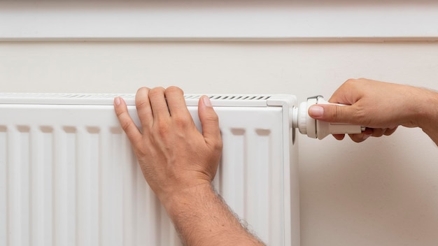 Man's hand adjusting the temperature of a radiator