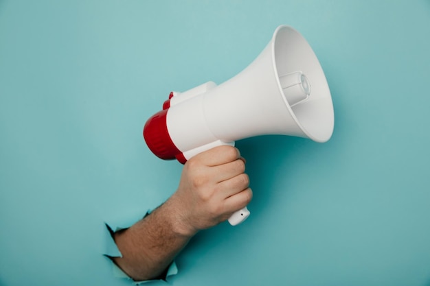 Photo man's hand arm hold megaphone isolated through torn blue paper