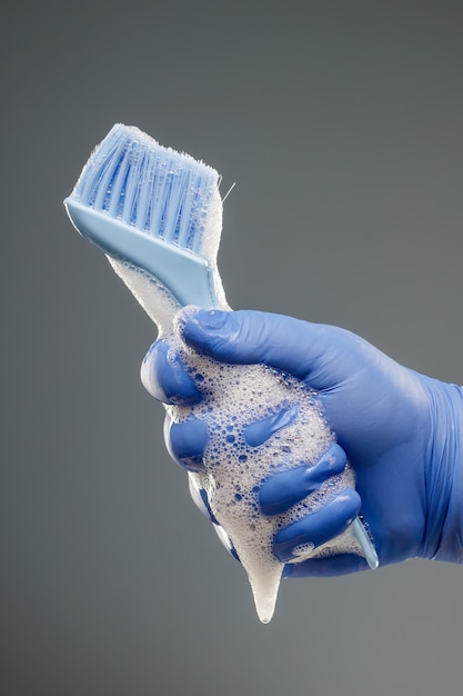 A man's hand in a blue glove holds a brush for cleaning