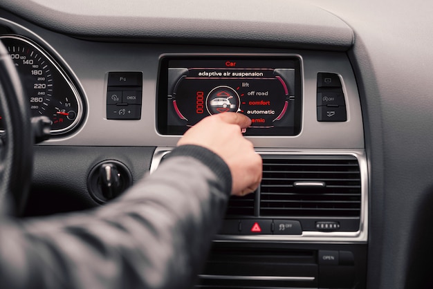 Man's hand chooses the style of driving on the board computer of the car.