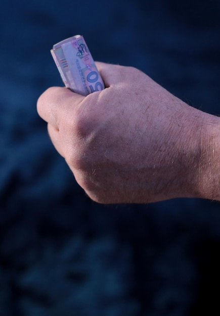 A man's hand clutching Ukrainian banknotes