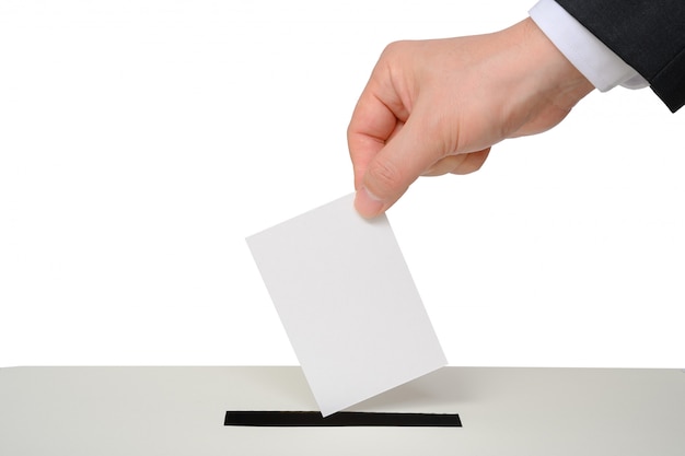 Man's hand down the ballot in the ballot box.