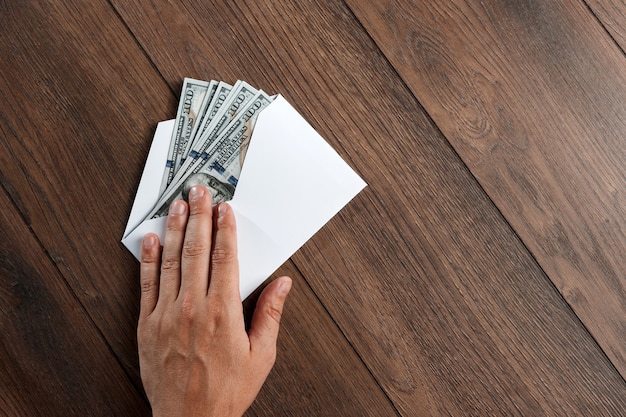 Man's hand en dollars van de VS in een witte envelop