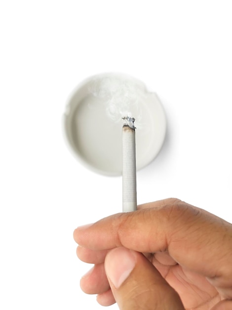 A man's hand flicks the ashes of the burning cigarette in the ashtray Smoking is harmful to health