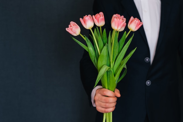 Man's hand giving a bouquet of pink tulips