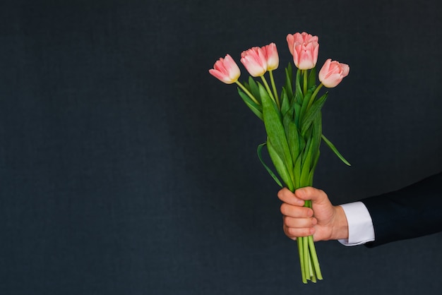 ピンクのチューリップの花束を与える人間の手