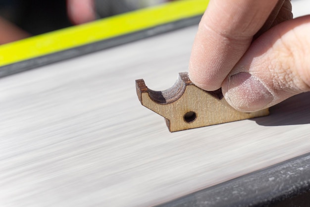 A man's hand grinds a wooden part on a machine carpenter's hand covered with dust holds the item