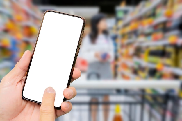 A man's hand holding a black smartphone Touch screen smartphone in a hand Women are shopping in supermarkets Select the product you want