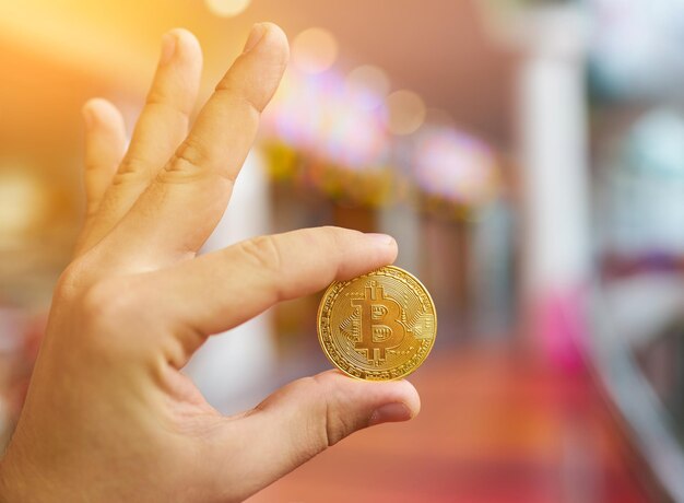 Man's hand holding golden Bitcoin