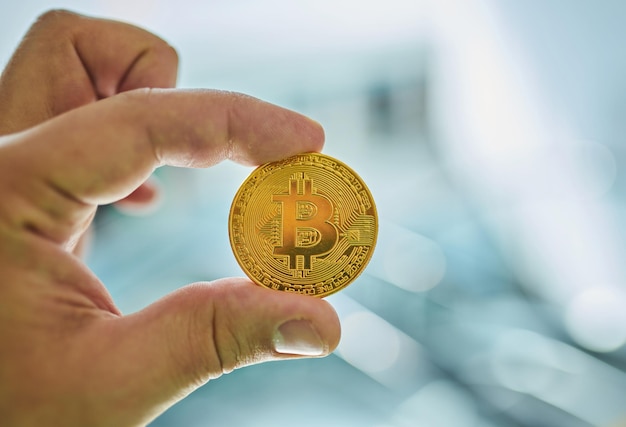 Man's hand holding golden Bitcoin