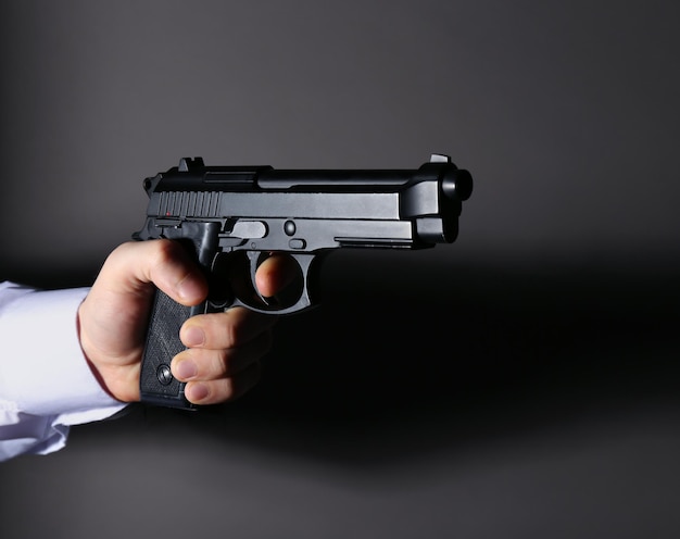 Man's hand holding gun on color background