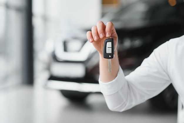 Man's hand holding modern car keys ready for rental car buyer's hand with keys