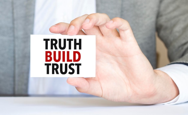 Man's hand holding paper sheet with truth build trust words