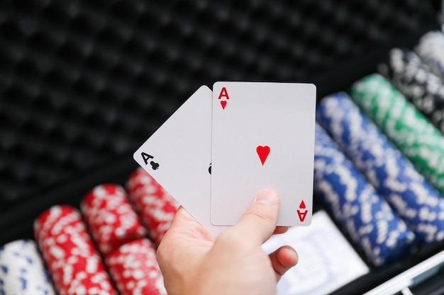 Foto la mano di un uomo che tiene una fiches da poker e una carta che dice carte da gioco.