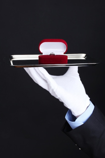 Man's hand holding ring in box on tray