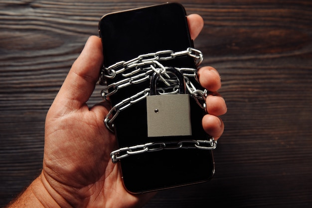 Man's hand holding a smartphone with padlock. Concept of smartphone protection against malware, antivirus