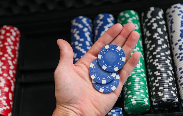 a man's hand holding a stack of poker chips.