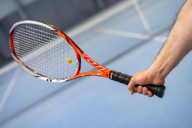 Man's hand holding tennis racket on tennis court