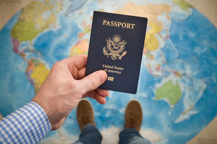 Photo man's hand holding us passport. map background. ready for traveling. open world.