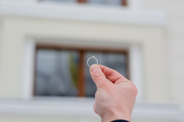 Man's hand holding a wedding ring